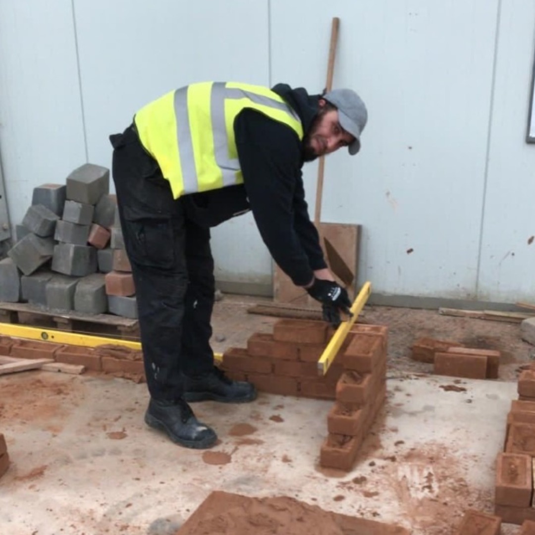 Construction student Radouine-Boujavmoune laying bricks in the construction block at the Wellington Road campus