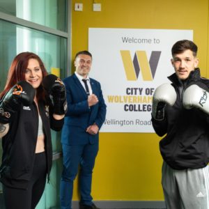 Three people in boxing gloves in front of a gollege logo at the launch of the new boxing academy