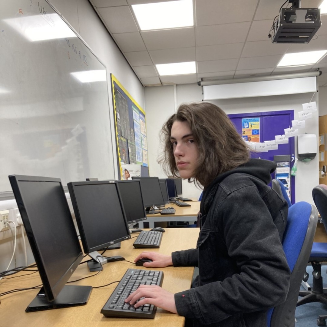 Student Ben Smith, wearing a black hoodie, sitting at a computer terminal