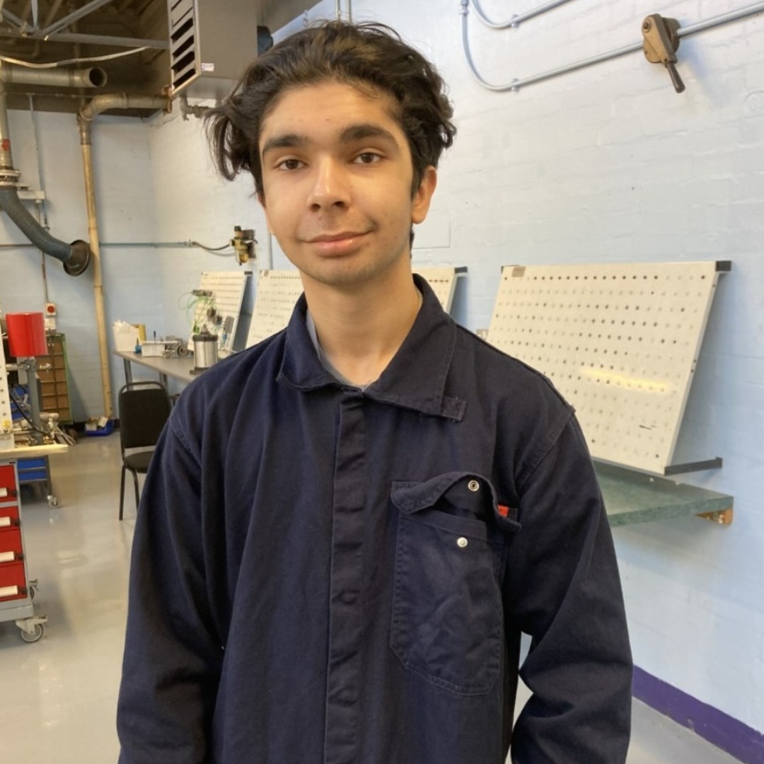 Engineering student Jeevan Singh, wearing dark blue overalls, pictured in the engineering workshop at the Paget Road campus