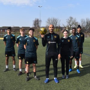 Former Wolves captain Karl Henry, wearing a black tracksuit, pictured centre with six college students wearing football kits
