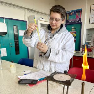 A-level student Paulina Patzova, wearing a white lab coat, carrying out an experiment in the science lab