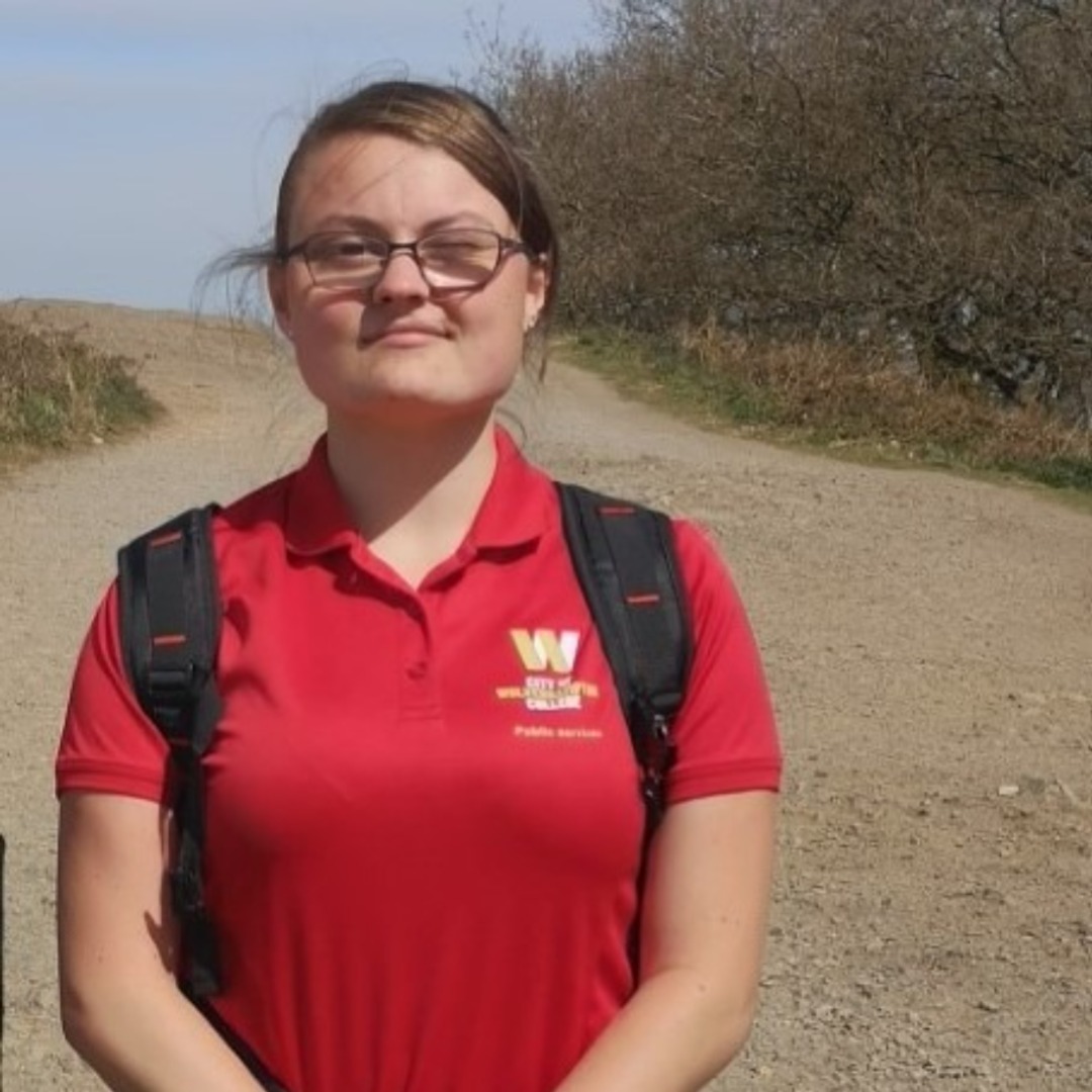 Former public services student Sophie Moreton, wearing a red polo shirt with the yellow and white college logo on the left hand side
