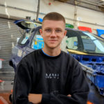 A picture of Tom behind a repaired motor vehicle