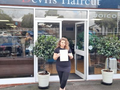 A picture of Rosie (student) outside a hair Salon holding a certificate