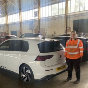Former motor vehicle student Keri-Leigh Price, wearing a hi-vis jacket and standing next to a white car in the workshop at Greenhous in Shrewwsbury
