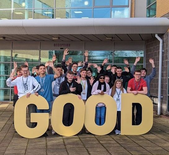A group of students standing behind giant letters spelling the word 'Good'