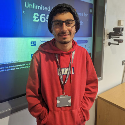 Bhuvanesh Mehton wearing a red top standing in front of a display board about the Midlands Metro