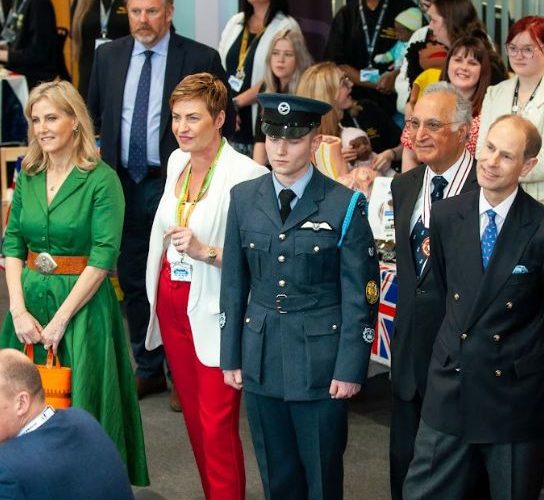 The Duchess of Edinburgh wearing a green dress, and the DUke of Edinburgh in a dark suit and blue tie with guests at the Coronation Big Lunch
