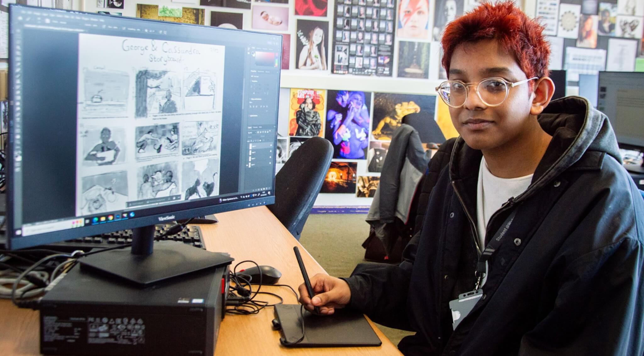 Art student SHafi Rahman sitting at a computer screen which displays his black and white illustrations