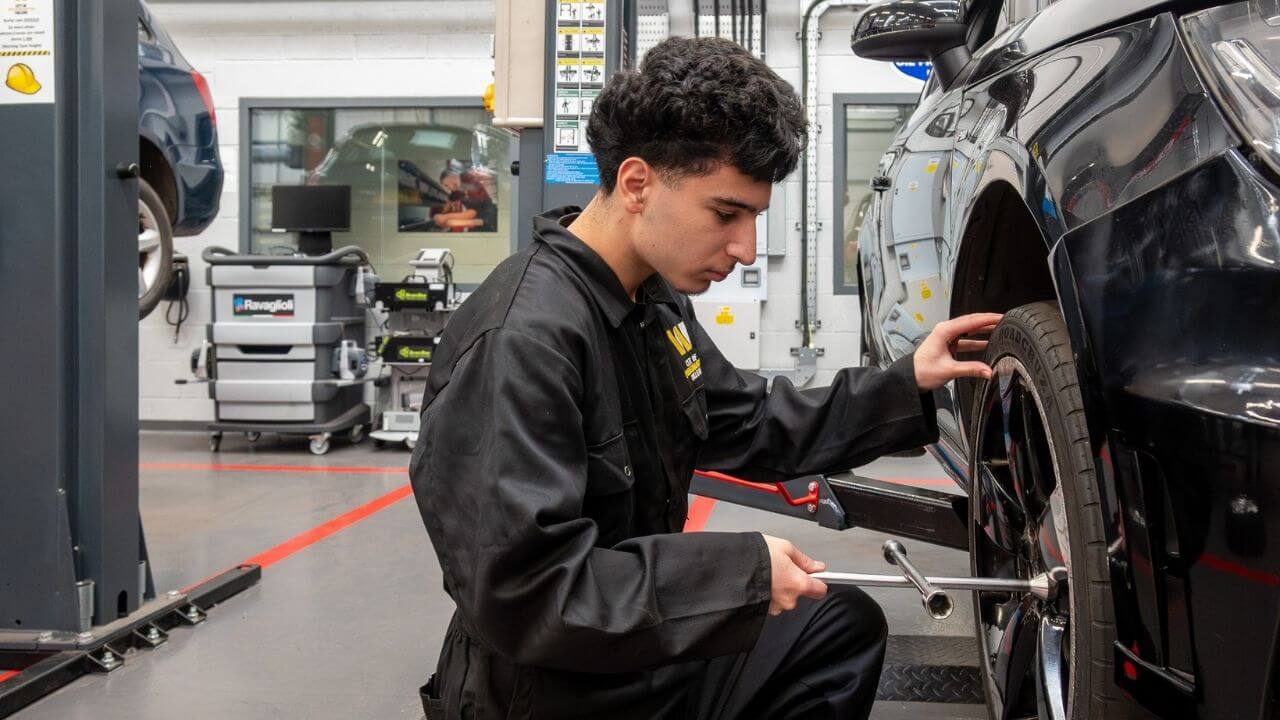 An automotive student taking off a tyre in the automotive workshop