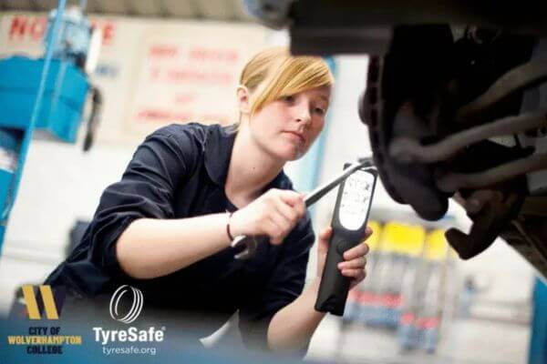 An image of a female automotive technician checking a trye